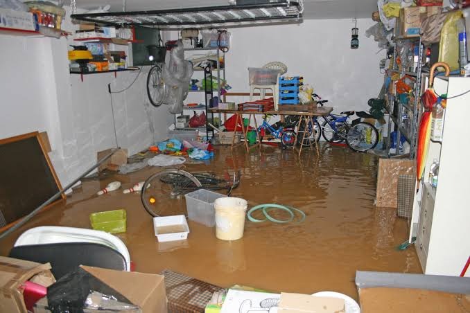 Flooded ground-level garage filled with muddy standing floodwater over household items